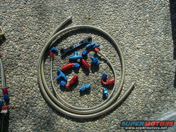 assortment of red and blue AN fittings and braided fuel line with a FRE wrench