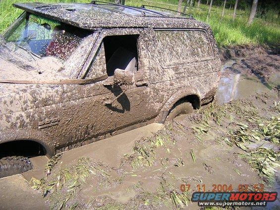 Mud-covered 1990 Ford Bronco stuck in mud, side view