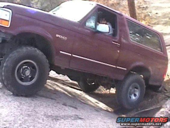 1993 Ford Bronco climbing over rocks on a trail