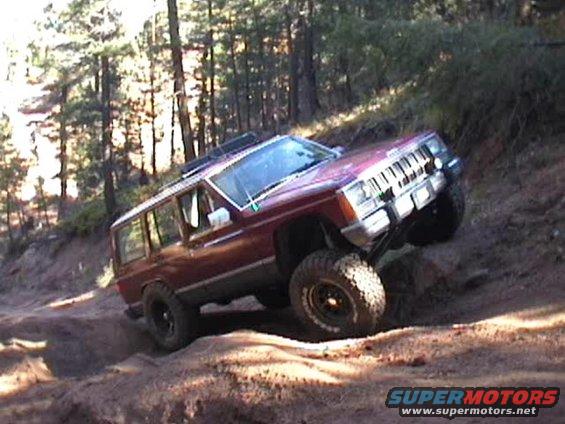 Red 1997 Jeep Cherokee XJ climbing a dirt hill off-road
