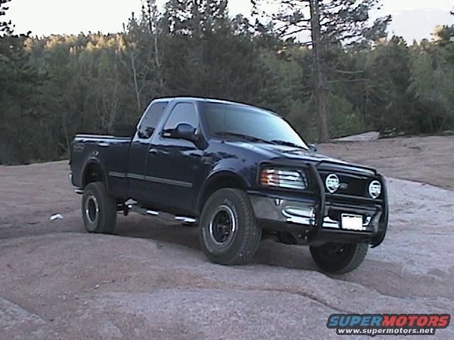 Dark blue pickup truck with bull bar parked on rocks