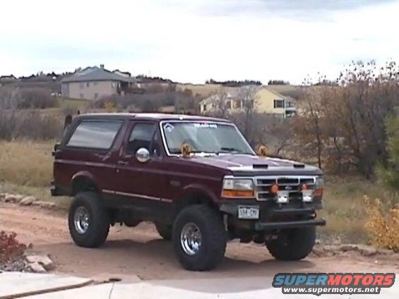 Maroon 1993 Ford Bronco 3q-front view with aftermarket wheels and lights