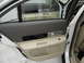 2002 Lincoln Town Car - The interior door panel of a white car shows beige and gray upholstery with chrome accents.