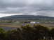 1988 Ford Bronco - A wide view of an airport with a town and a mountain in the background on a cloudy day.