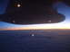 1988 Ford Bronco - View from an airplane window shows the wing and lights against a sunrise over a cloud layer.