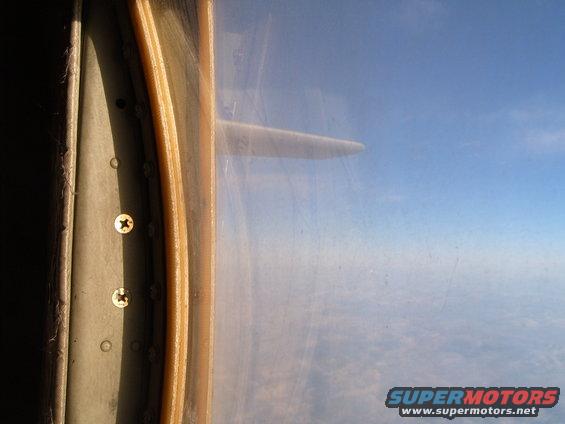 View of airplane wing and sky from inside an aircraft cabin