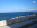 1988 Ford Bronco - A scenic view of the ocean with waves crashing on rocks, bordered by a stone wall and tiled walkway.