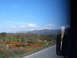 1988 Ford Bronco - A scenic view of rolling hills and mountains under a blue sky, with a road in the foreground.