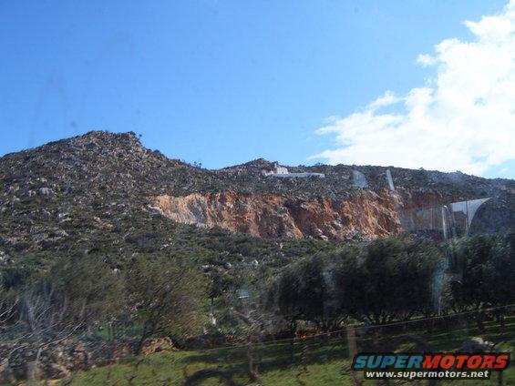 Rocky hillside with trees and a building on top