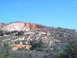 1988 Ford Bronco - View of a rocky hillside with several small structures and a quarry, under a bright blue sky.