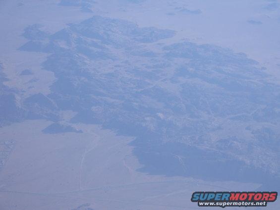 Aerial view of mountains and desert landscape with Supermotors.net watermark