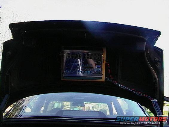 Car trunk interior with aftermarket stereo mounted on the lid, wires visible
