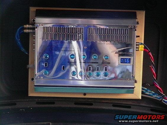 Car stereo amplifier with blue lights and digital display showing 11.6