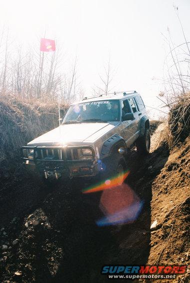 Silver Jeep Cherokee XJ off-roading on a dirt path