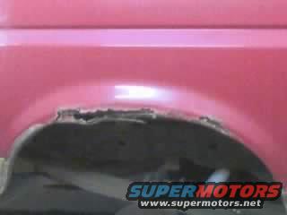 Close-up of rusted rear wheel well on a pink vehicle