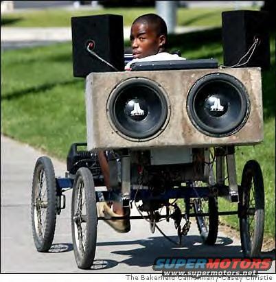 Custom vehicle with two large subwoofers and two smaller speakers, driven by a young person