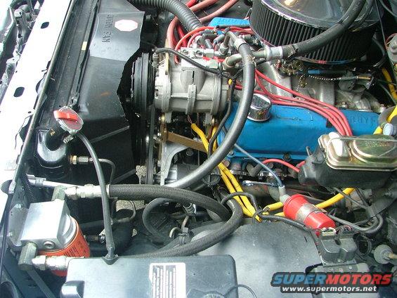 Engine bay with blue valve covers, red spark plug wires, and a chrome air filter housing. A SuperMotors logo is visible at the bottom right