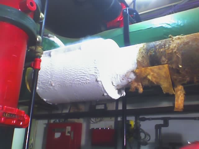 Industrial pipes with white insulation and some exposed rusty metal