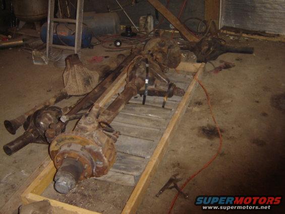 Several rusty vehicle axles on a wooden pallet