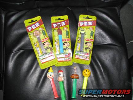 Three PEZ dispensers in packaging and four loose dispensers on a black surface