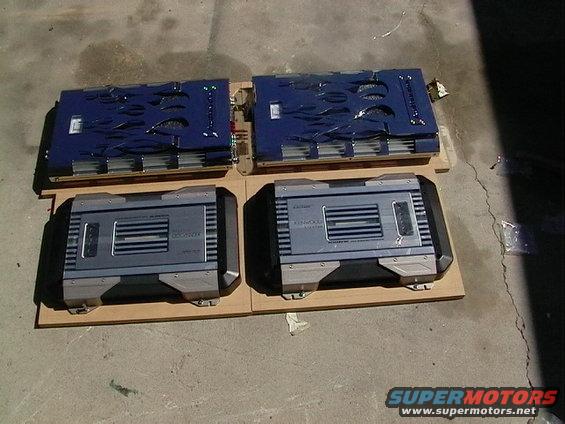 Four car amplifiers on wooden boards, two blue and two silver