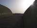 1988 Ford Bronco - A desolate scene two Quonset huts under a bright, hazy sky, with distant hills on the horizon.
