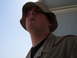 1988 Ford Bronco - A man in a bucket hat and camouflage shirt is seen from a low angle against a clear blue sky.