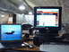 1988 Ford Bronco - A desk setup features two computers, one displaying a jet and the other a website, with lockers visible behind.