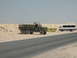 1988 Ford Bronco - A military truck and a bus are parked in a desert landscape.