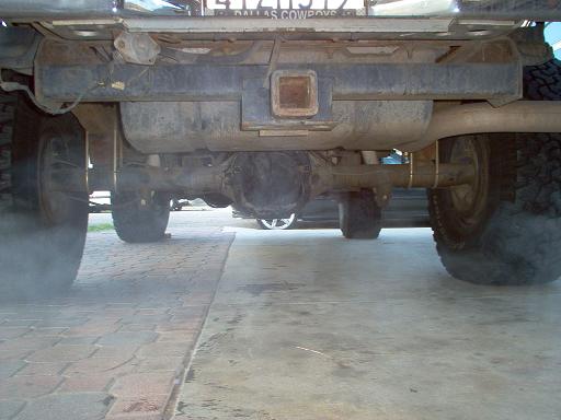 Underside view of a truck's rear axle, differential, exhaust, and tires