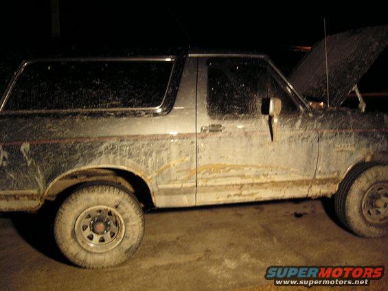Side view of a muddy 1989 Ford Bronco with hood open