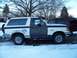 1990 Ford Bronco - A two-tone Ford Bronco sits in a snowy area, with a dark SUV parked behind it.