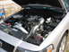 1997 Ford Crown Victoria - The engine bay of a silver sedan, modified with a turbocharger and custom intake, is shown with the hood open.