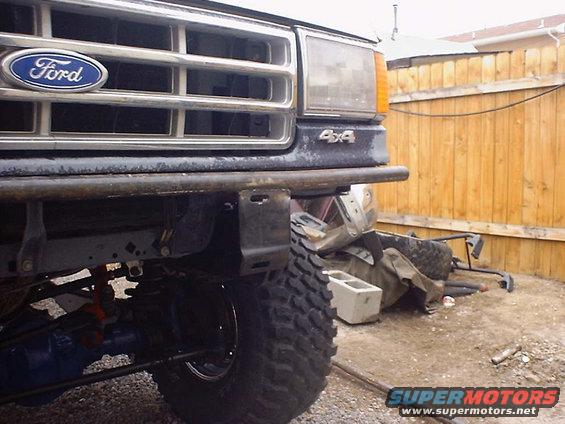 Ford grille with blue oval badge and 4x4 emblem, custom tube bumper, large tire, and suspension parts visible