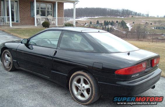 Black 1994 Ford Probe coupe parked on gravel driveway, rear 3/4 view