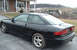 1994 Ford Probe - A black 1994 Ford Probe coupe is seen from the rear 3/4 angle in front of a brick house.