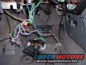 Mess of wires and electrical components under a car's dashboard