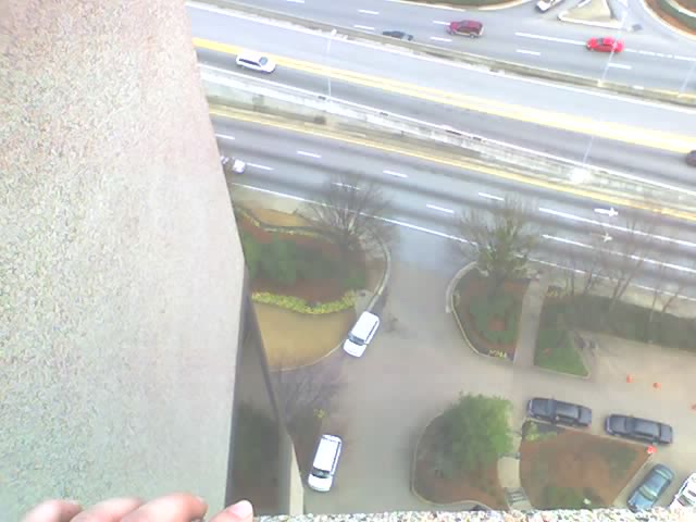 Aerial view of a highway and parking lot with several cars visible