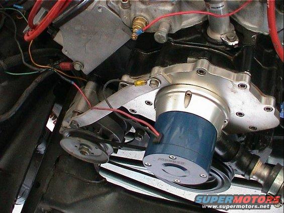 Close-up of an electric water pump with blue housing mounted on an engine block, wires and pulleys visible