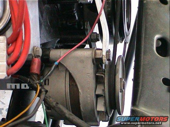 Close-up of an engine's alternator with red wires and a belt