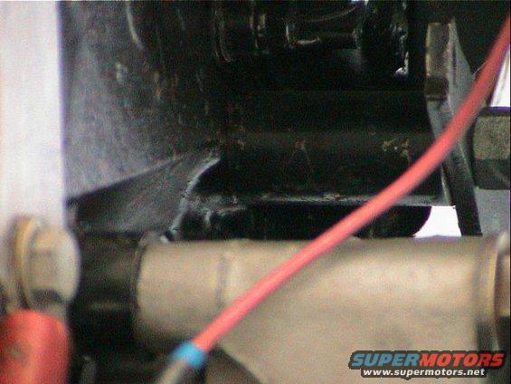 Close-up of engine bay with red wire and metal components