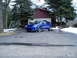 2003 Mazda Protege - A blue 2003 Mazda Protege sedan is parked in a driveway in front of a house.