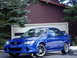 2003 Mazda Protege - A blue 2003 Mazda Protege sedan is parked in front of a house with a garage door.