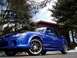 2003 Mazda Protege - A blue 2003 Mazda Protege sedan with custom wheels and body kit is parked in front of a house.