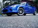 2003 Mazda Protege - A blue sedan with custom wheels is viewed from a low angle, its front three-quarter profile.