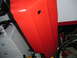 1994 Ford Bronco - A close-up shot focuses on a vibrant red vehicle panel, revealing a small, dark circular opening.