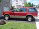 1992 Ford Explorer - Side view of a red 1992 Ford Explorer parked on a paved driveway next to a brick house.