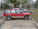 1992 Ford Explorer - A red SUV is parked in a lot next to a green truck.