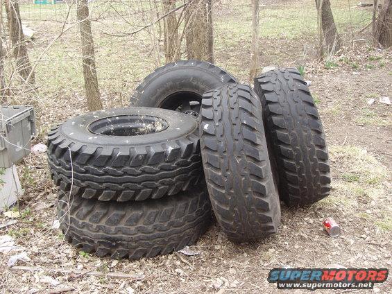 Pile of four large off-road tires stacked outdoors