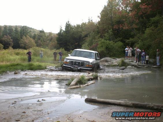 1995 Ford Bronco stuck in a muddy water crossing with people watching